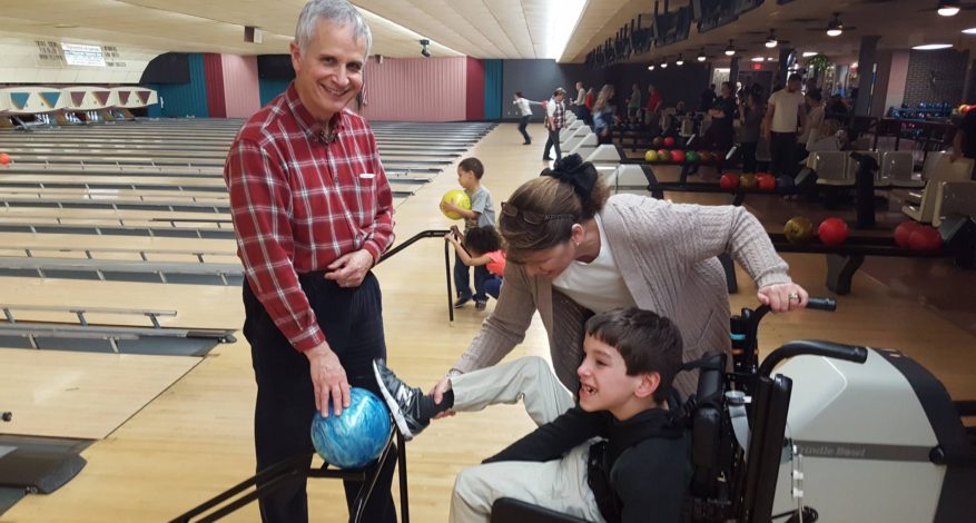 child bowling with family