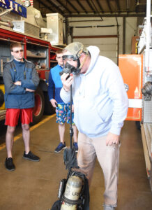 Matthew and Michael watch as Bob demonstrates gas mask